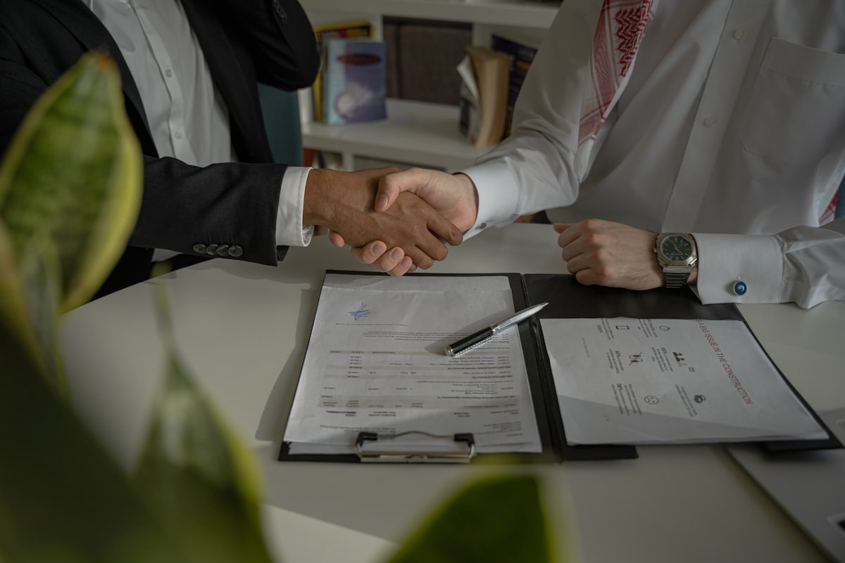 Two people shaking hands over a signed document