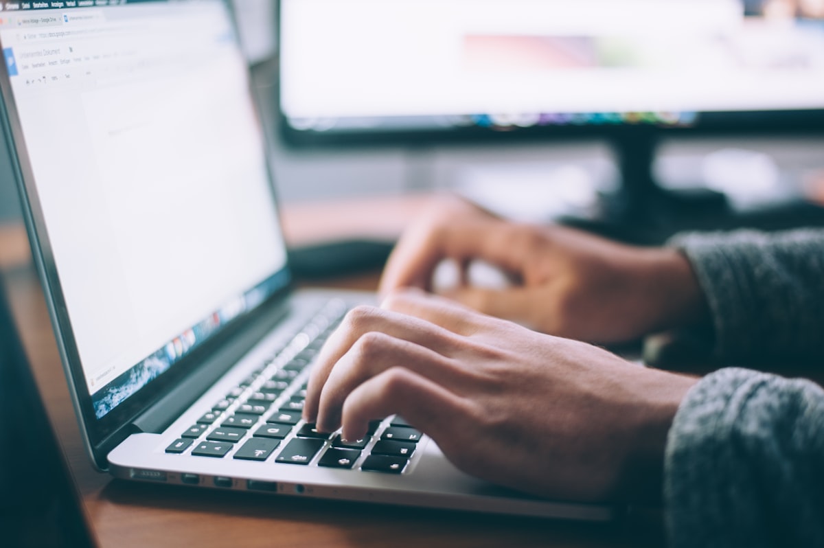 A person typing on a laptop at a desk
